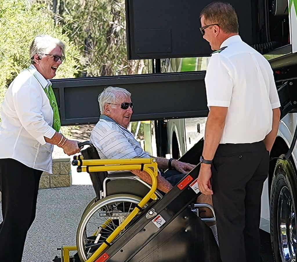 Man in wheelchair being assisted onto bus